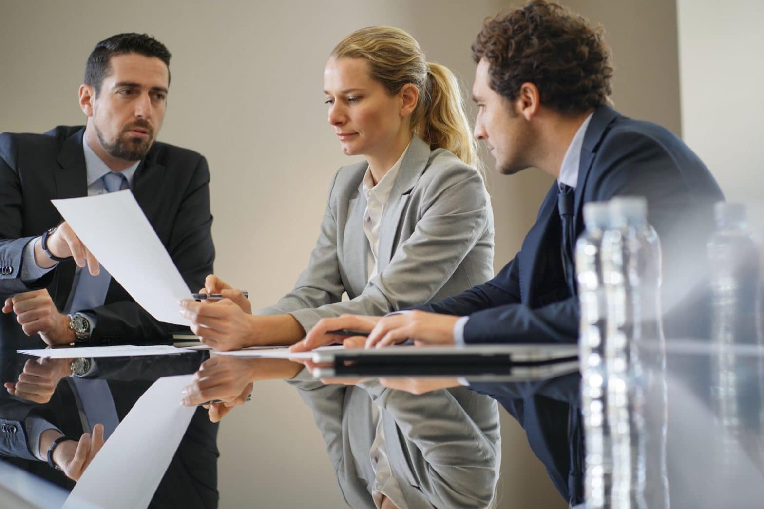 Three people sitting at a desk going over paperwork