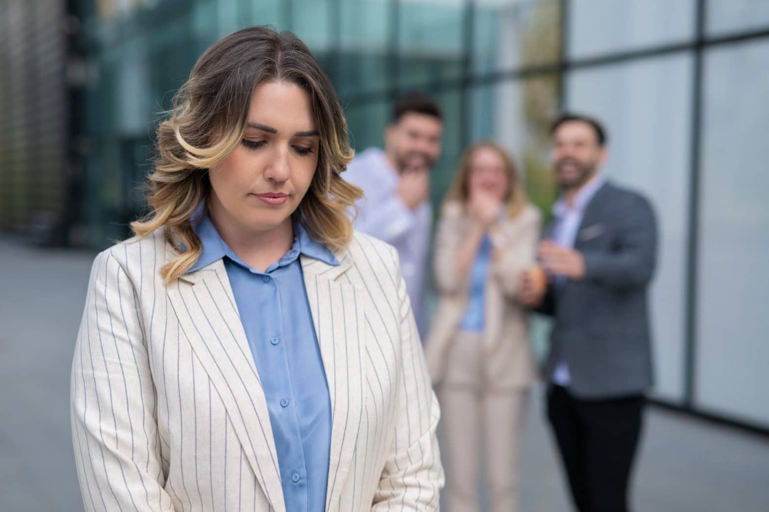 One person standing in the front looking sad with three other people standing behind her blurred
